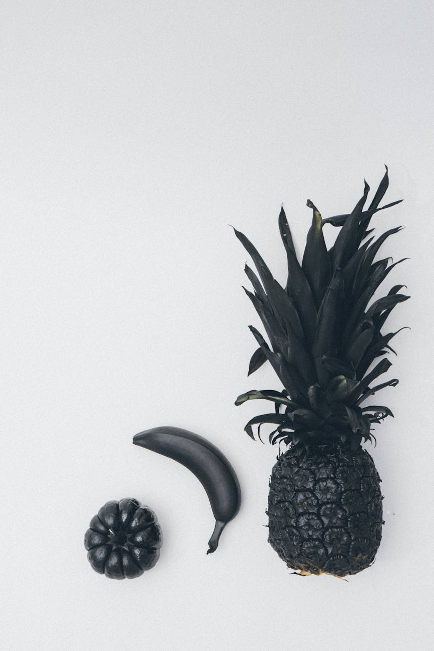 Artistic black and white photo of a pineapple, banana, and pumpkin.