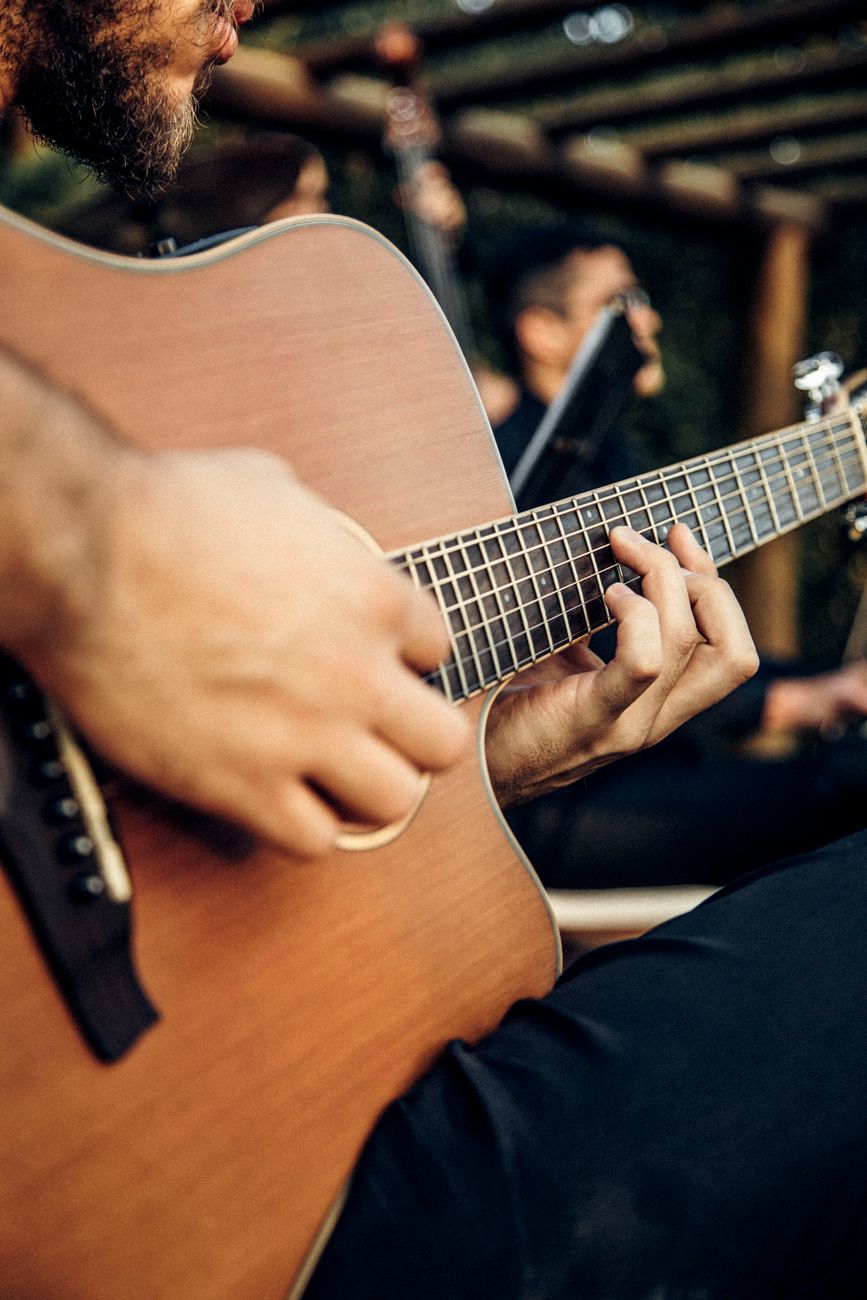 A close-up shot of a man strumming an acoustic guitar outdoors, emphasizing musical expression.