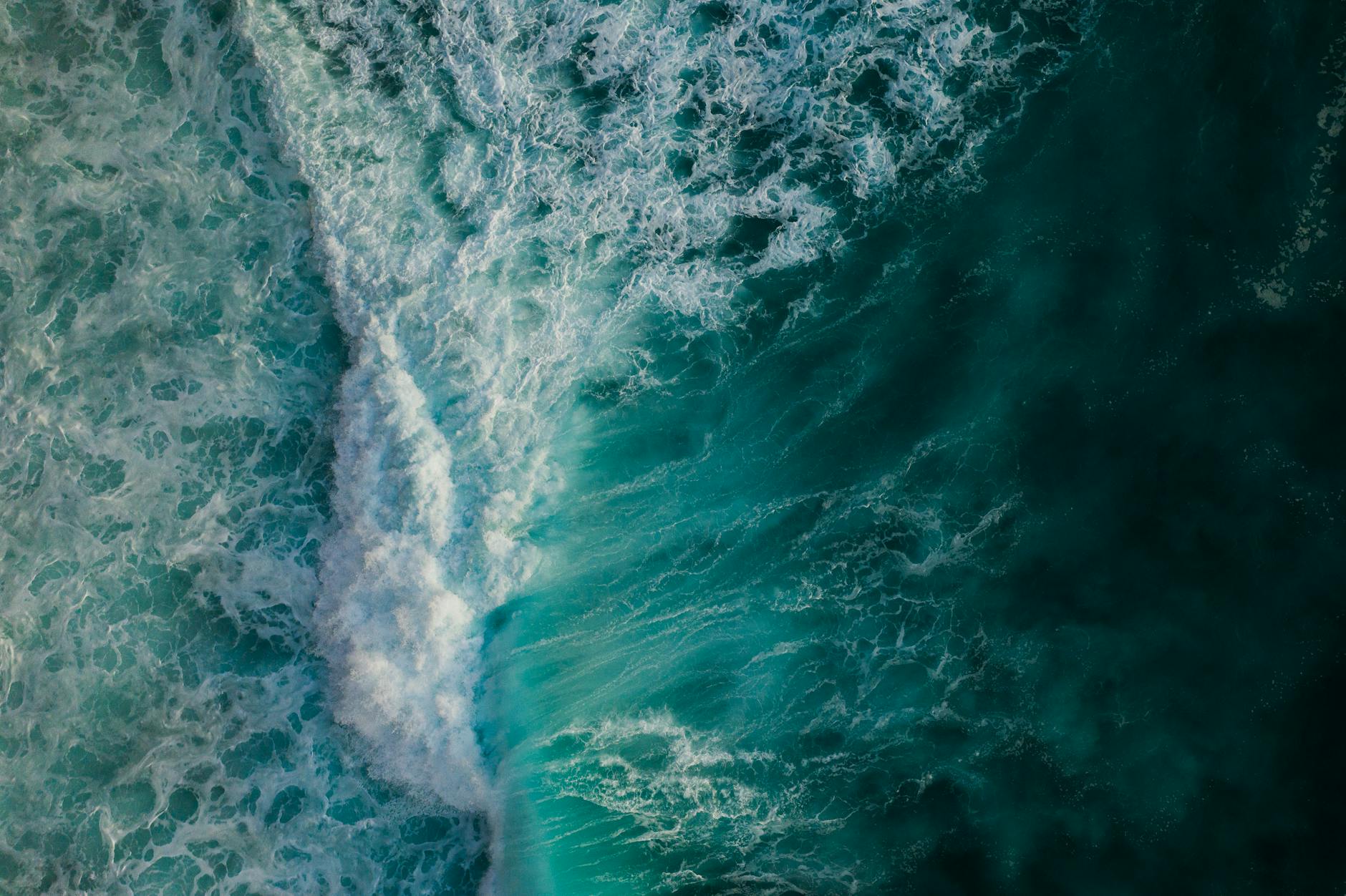 Dynamic aerial view capturing the vibrant movement of crashing ocean waves with foam and splash.