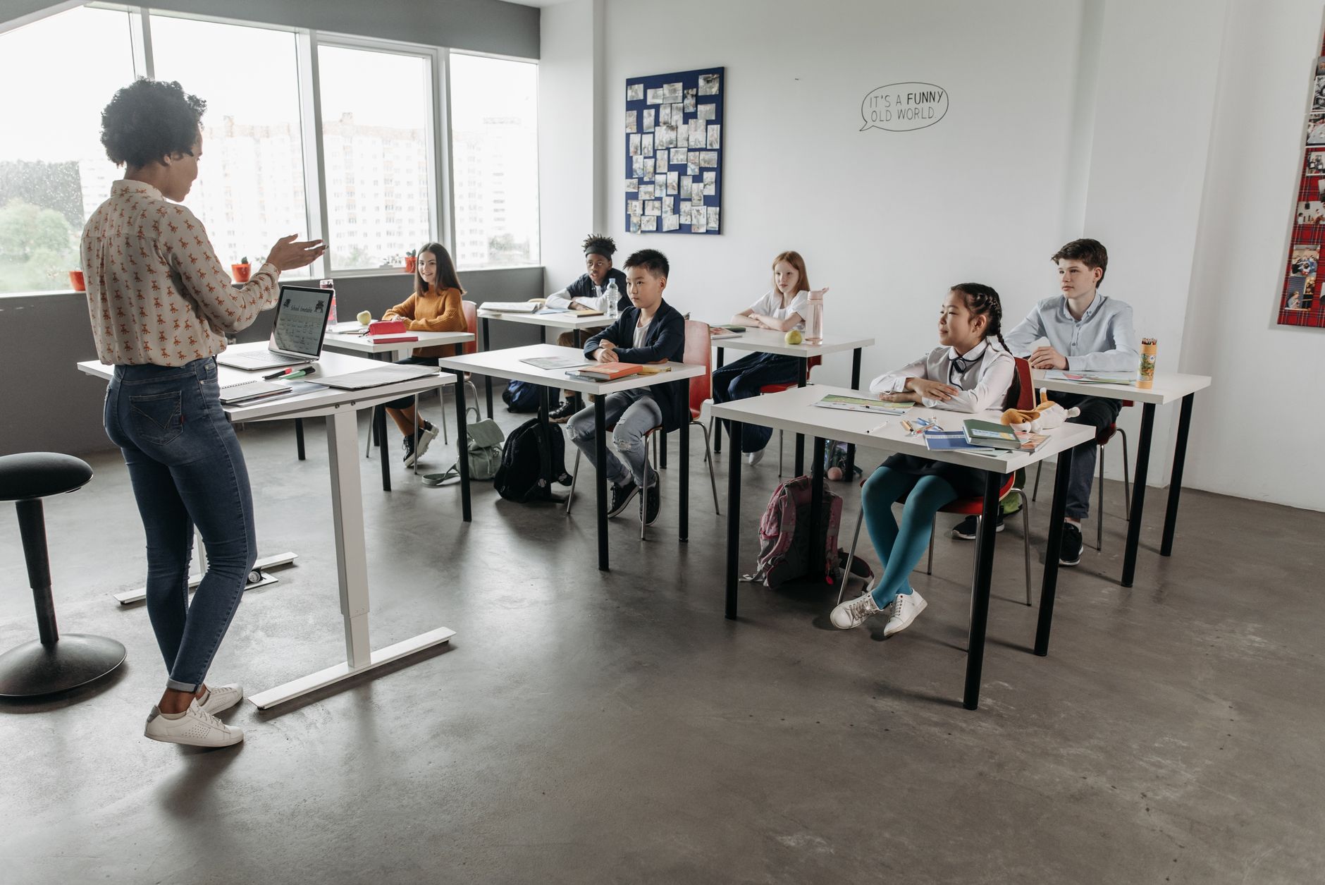 Teacher interacting with students in a modern classroom, fostering a diverse and engaging educational environment.