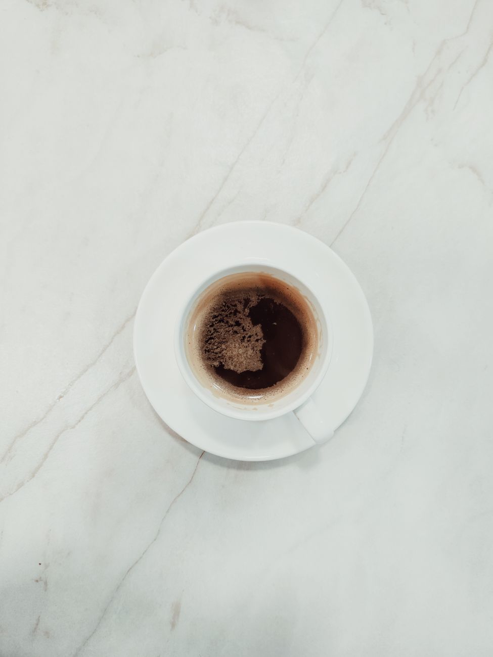 A minimalist flat lay of a coffee cup on a marble surface, ideal for coffee and lifestyle themed content.