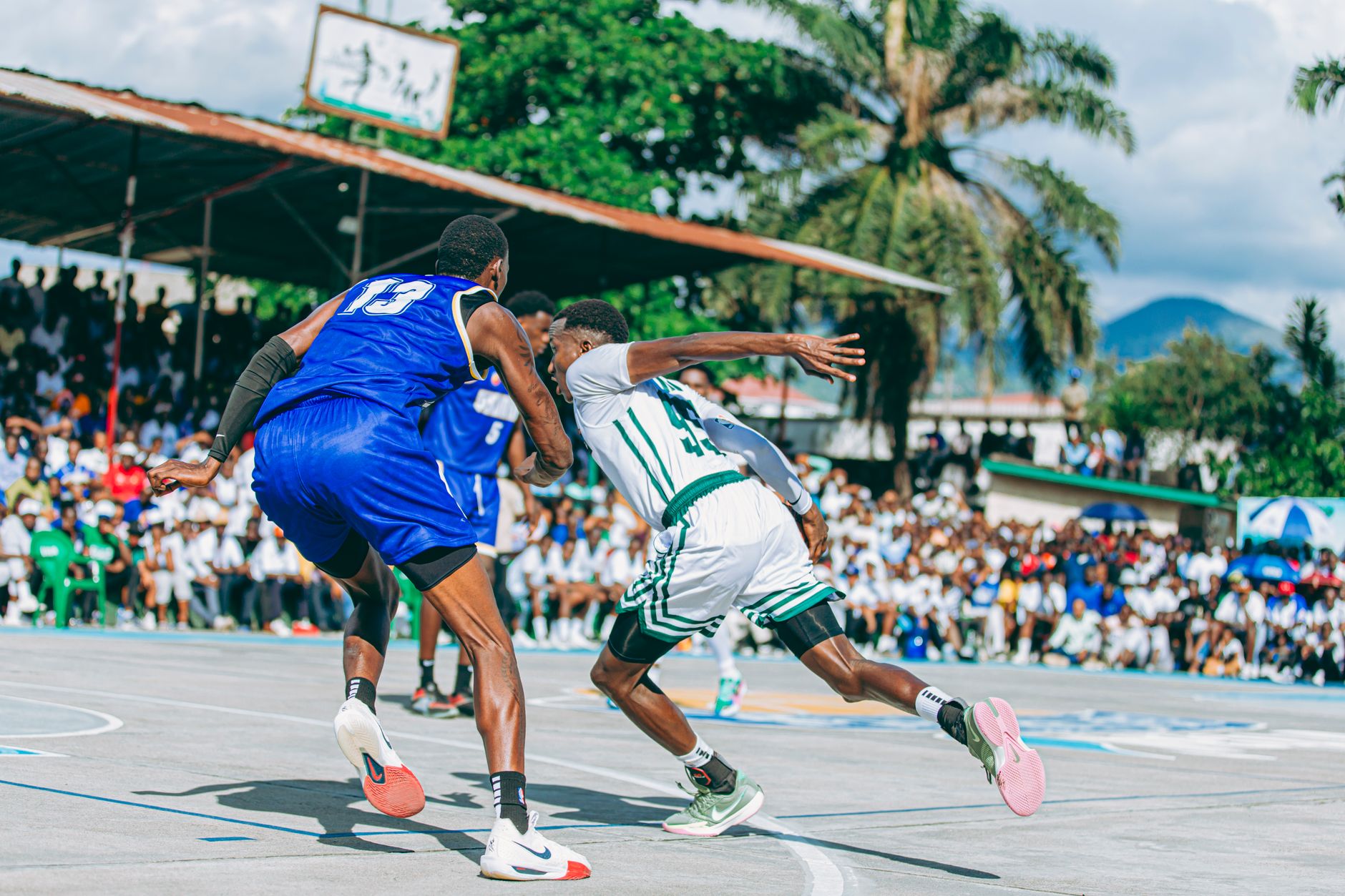 Players compete in an exciting outdoor basketball game with a lively crowd watching.