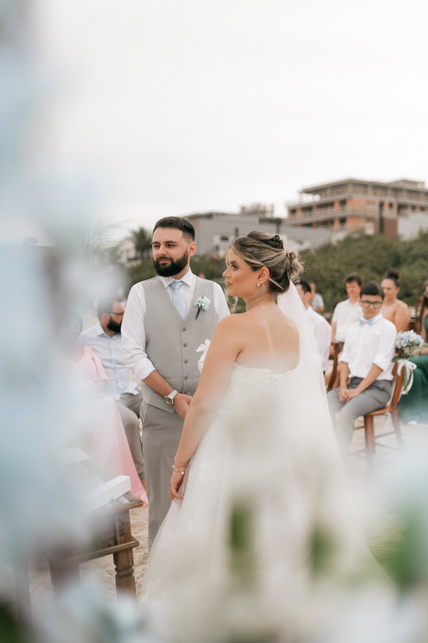 A bride and groom at an outdoor wedding ceremony surrounded by guests.