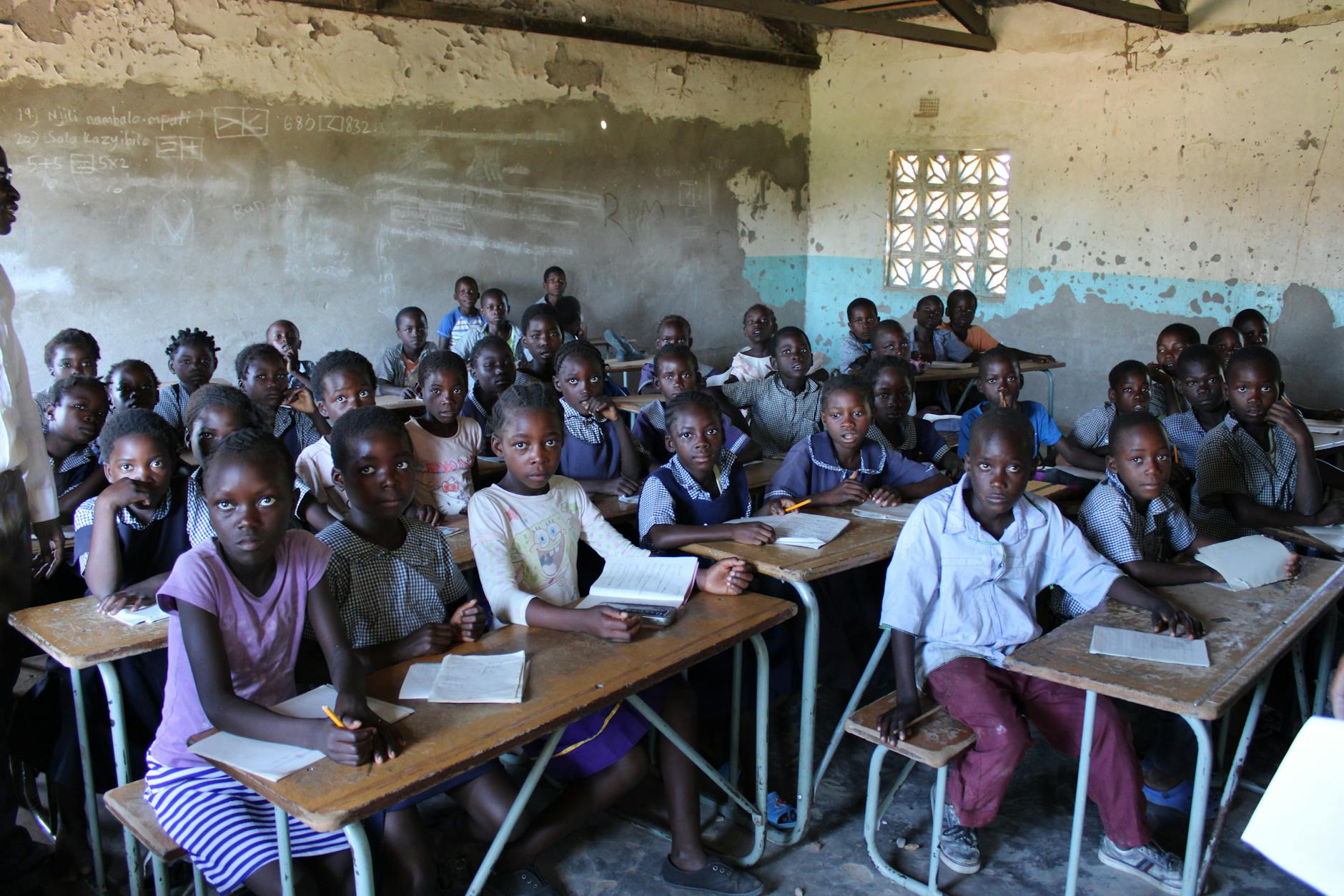 A group of children in a classroom in Zambia focused on their studies.