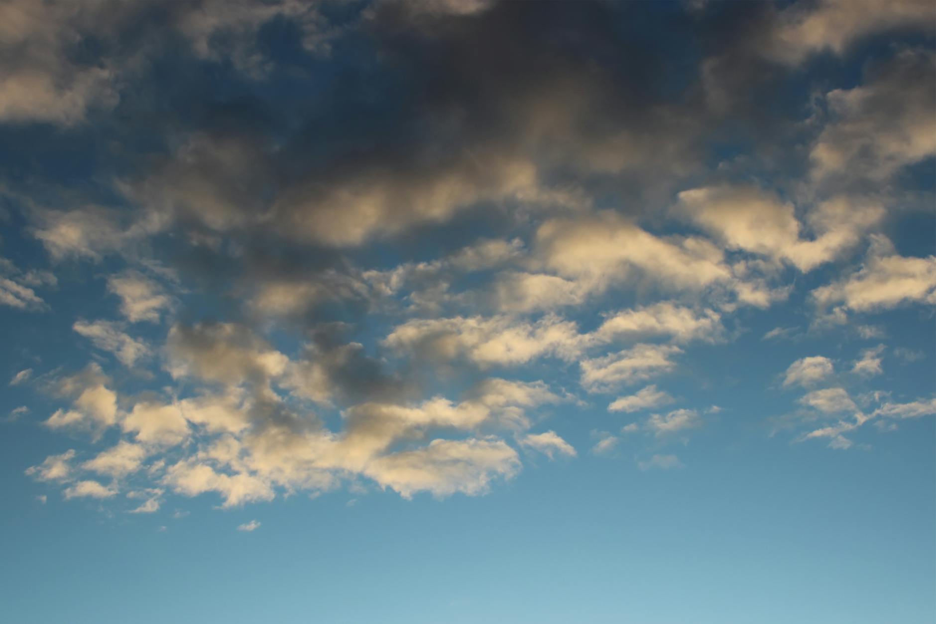 A peaceful sky featuring fluffy white clouds against a deep blue background.
