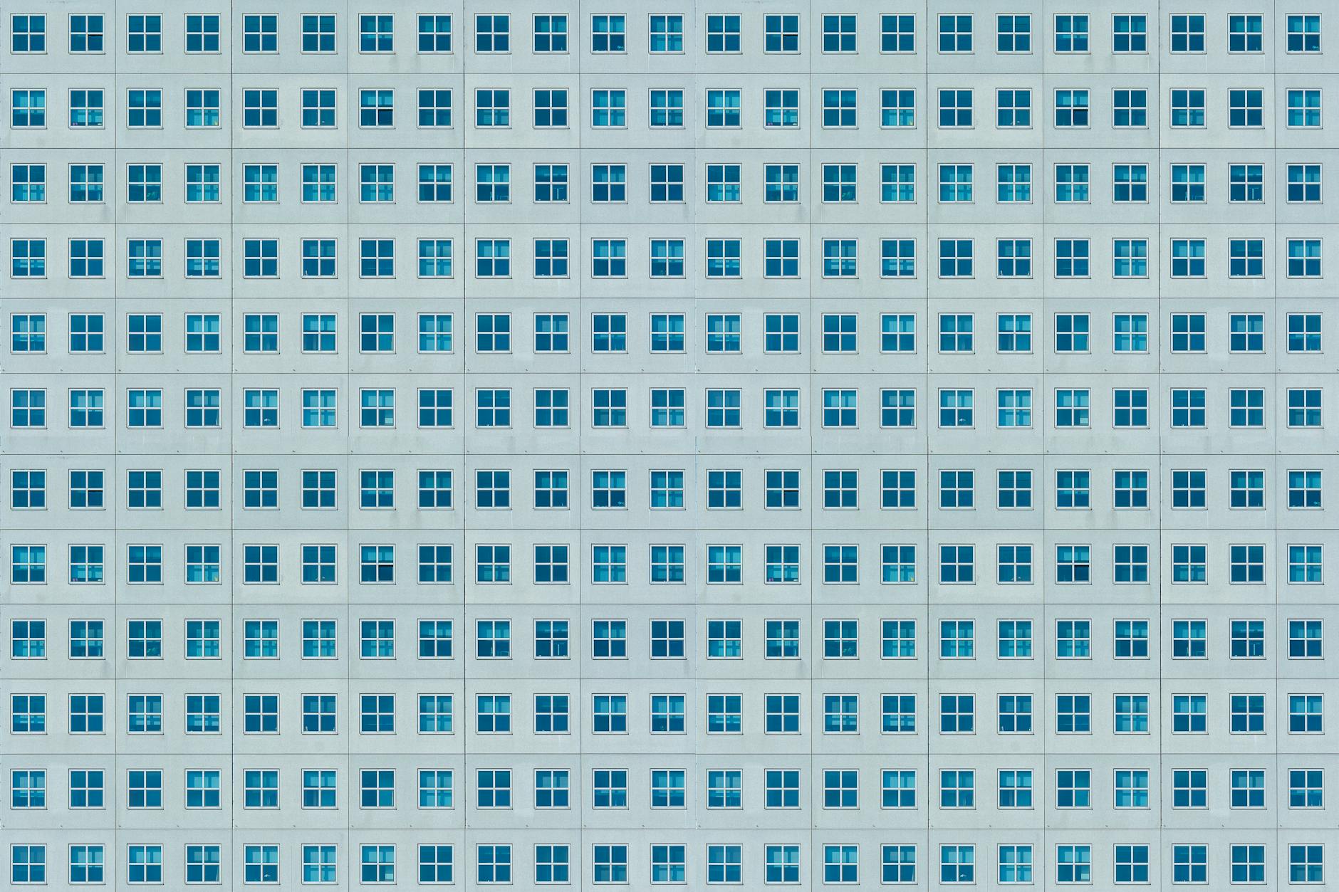 Facade of a modern building with symmetrical, repetitive window patterns creating an urban texture.