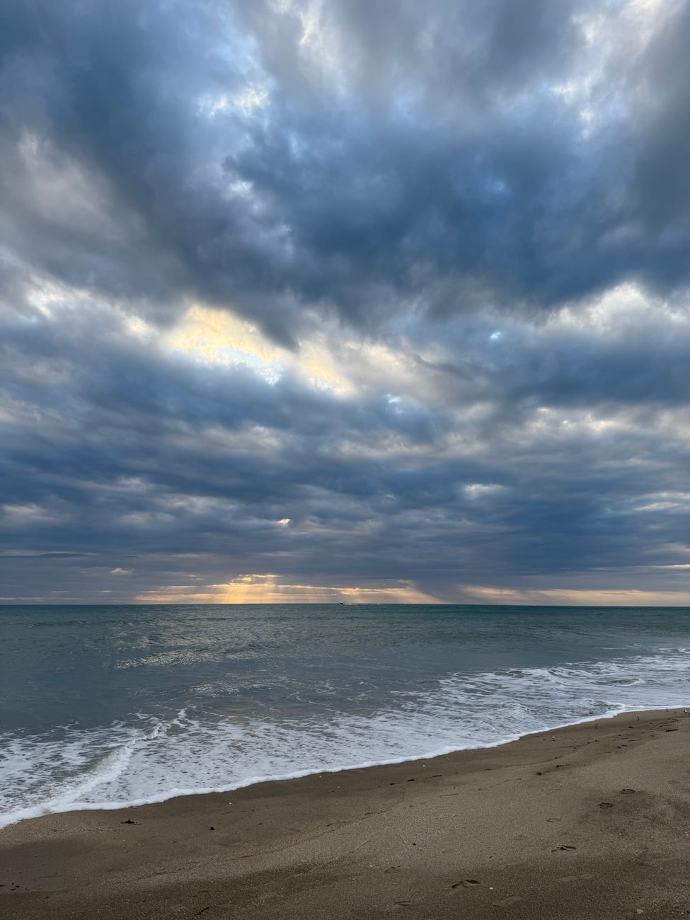 Capture of a serene sunrise over the calm ocean at Jensen Beach, Florida, with dramatic clouds.