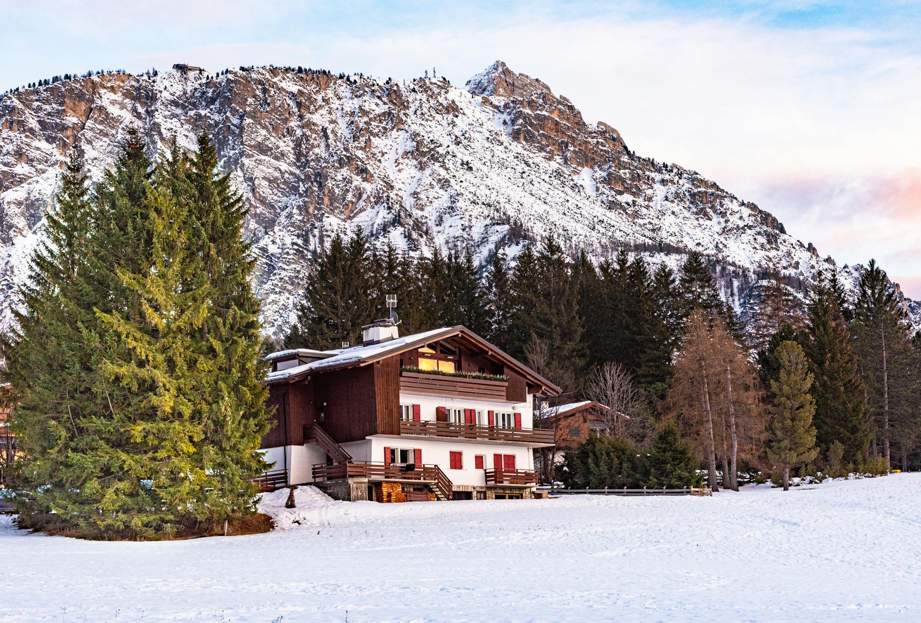 A picturesque alpine chalet surrounded by snowy mountains in Cortina d'Ampezzo, Italy.