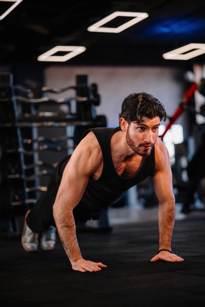 A muscular man performing push-ups in a modern gym, demonstrating strength and fitness.
