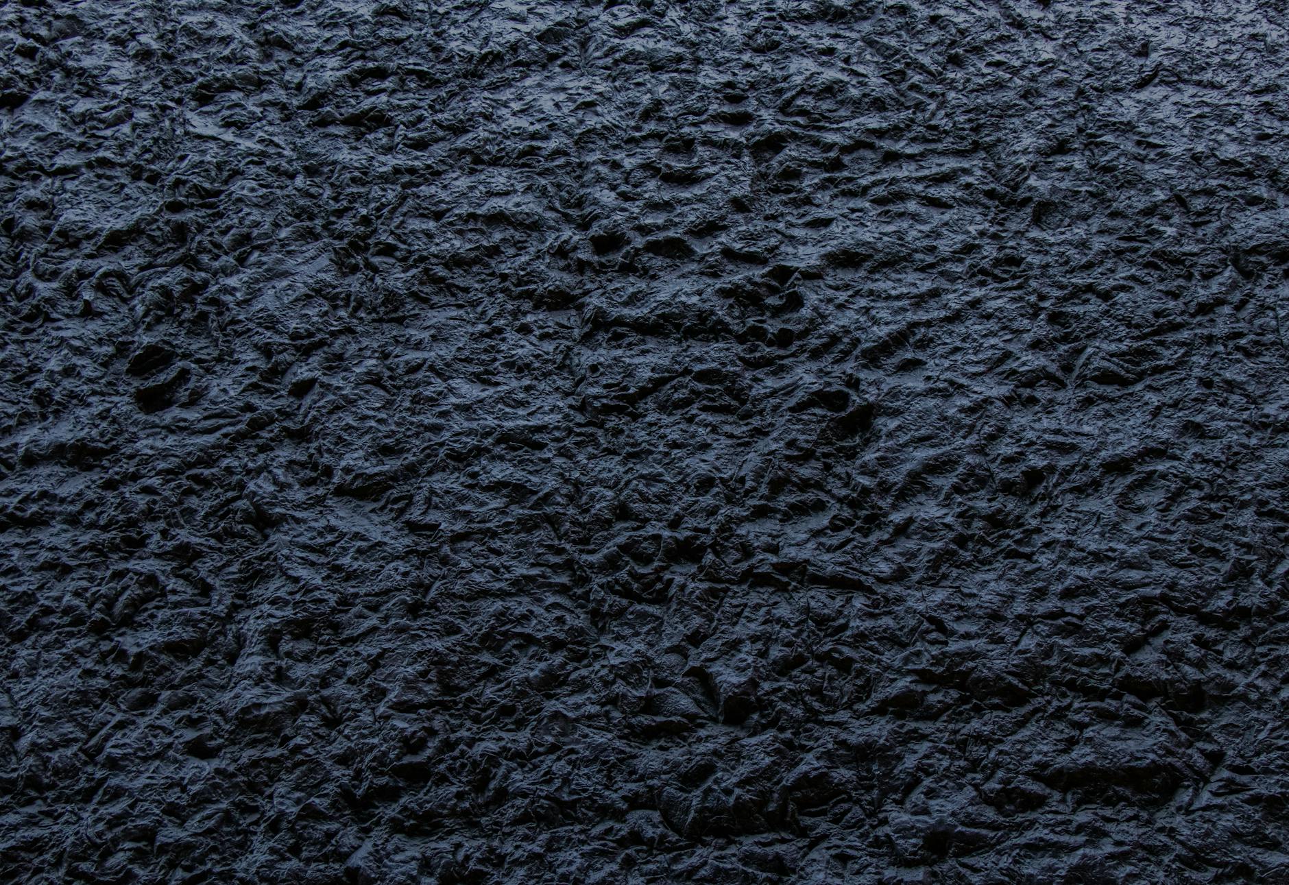 Close-up of a dark, rough textured stone surface providing an abstract background.