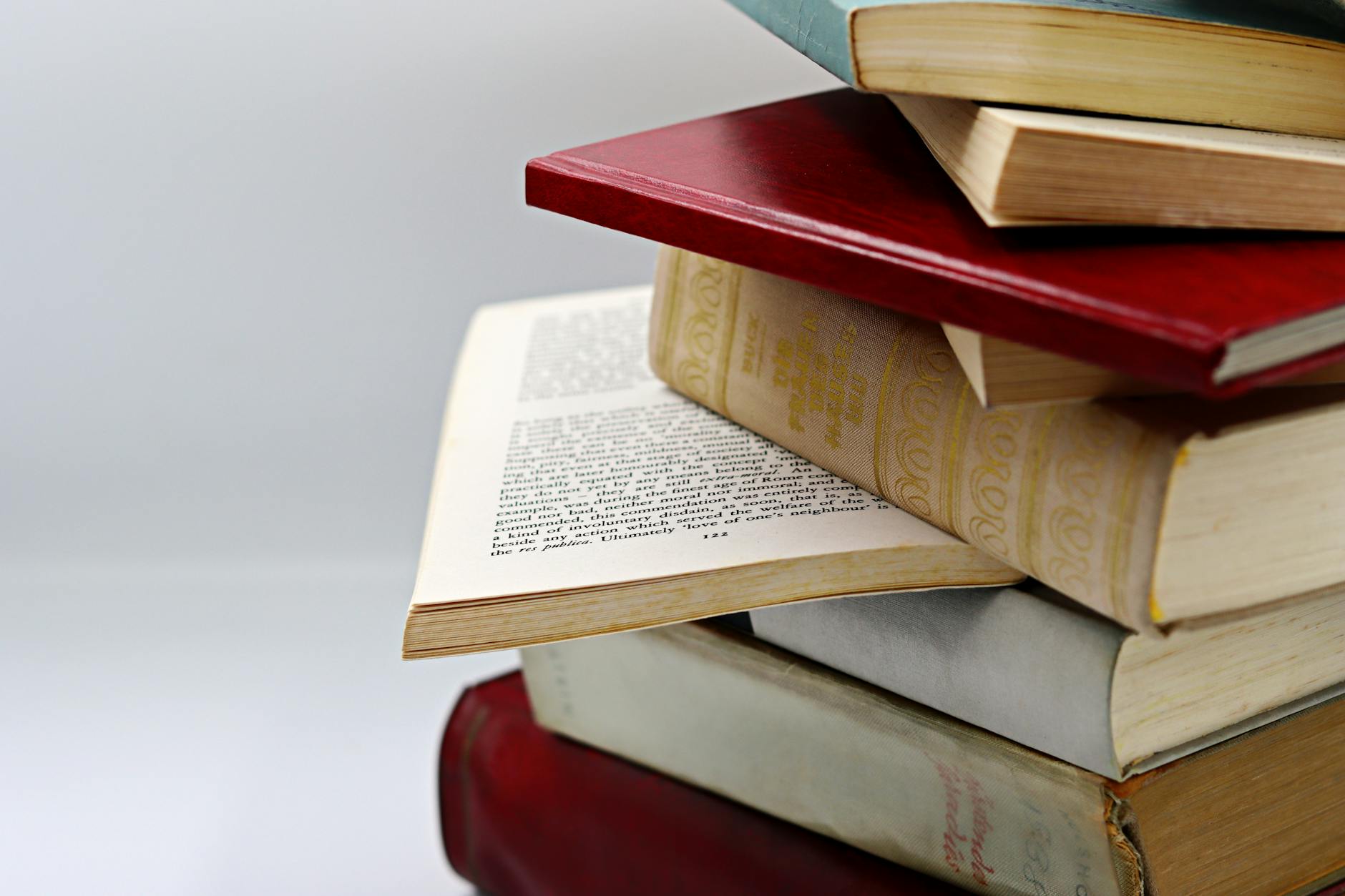 A close-up view of a stack of vintage and modern books with a focus on open pages, offering a sense of knowledge and history.