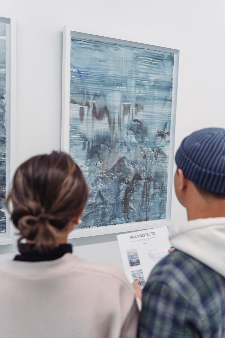Two people view abstract art in a modern gallery, focusing on interpretations.