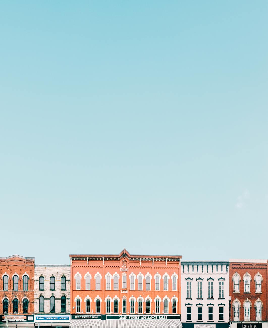 Vivid storefronts in a quaint small town against a clear blue sky creating a minimalistic vibe.