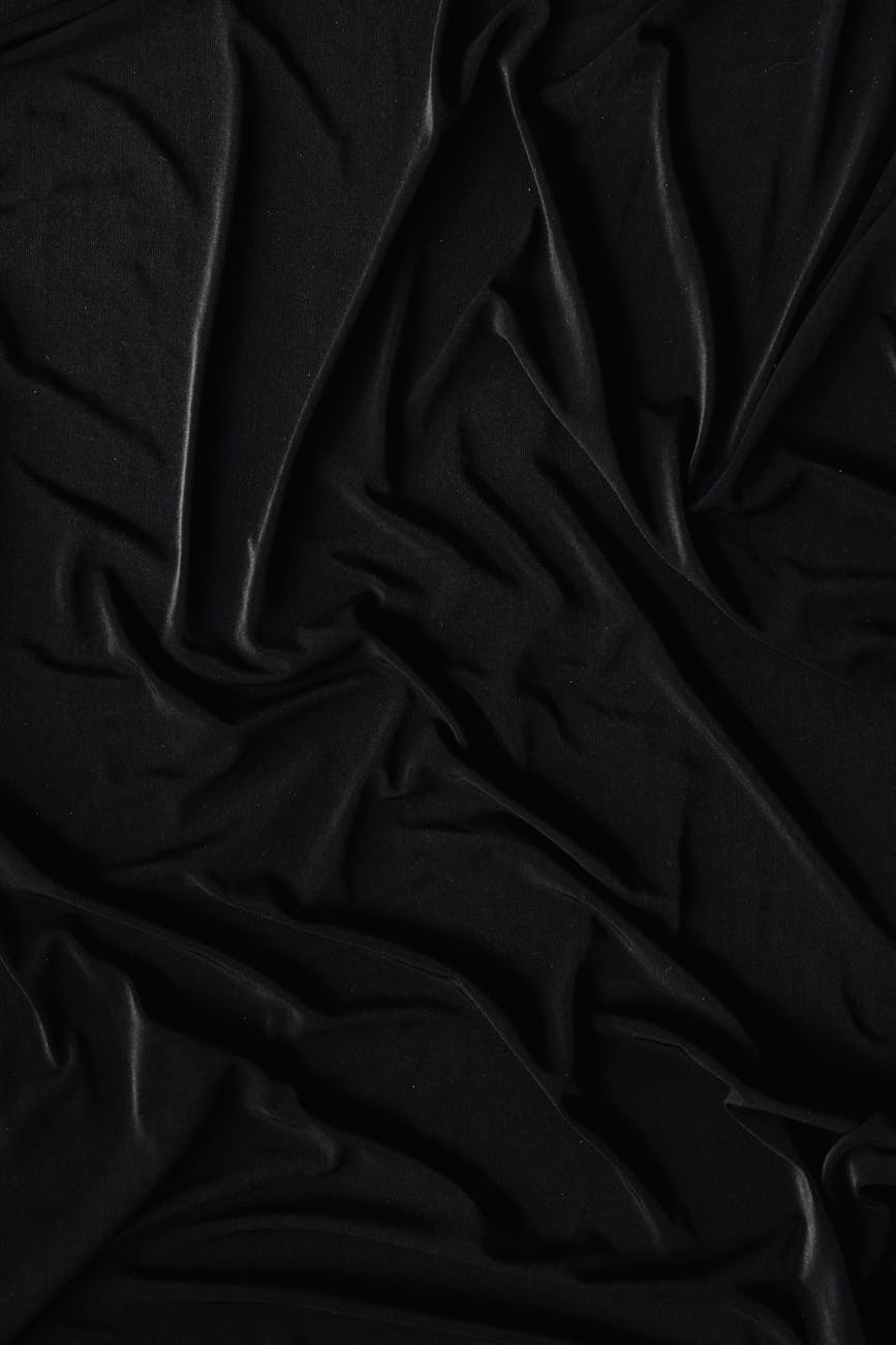 A detailed shot of a crumpled black fabric, showcasing its smooth and wrinkled texture in a monochromatic tone.