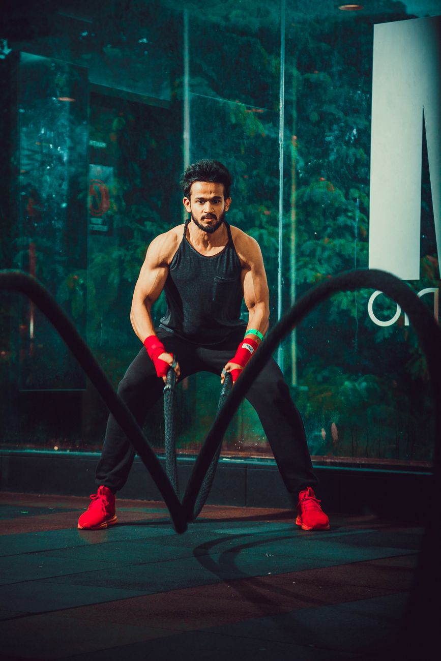 Man performing an intense workout with battle ropes in a modern gym setting, showcasing strength and focus.