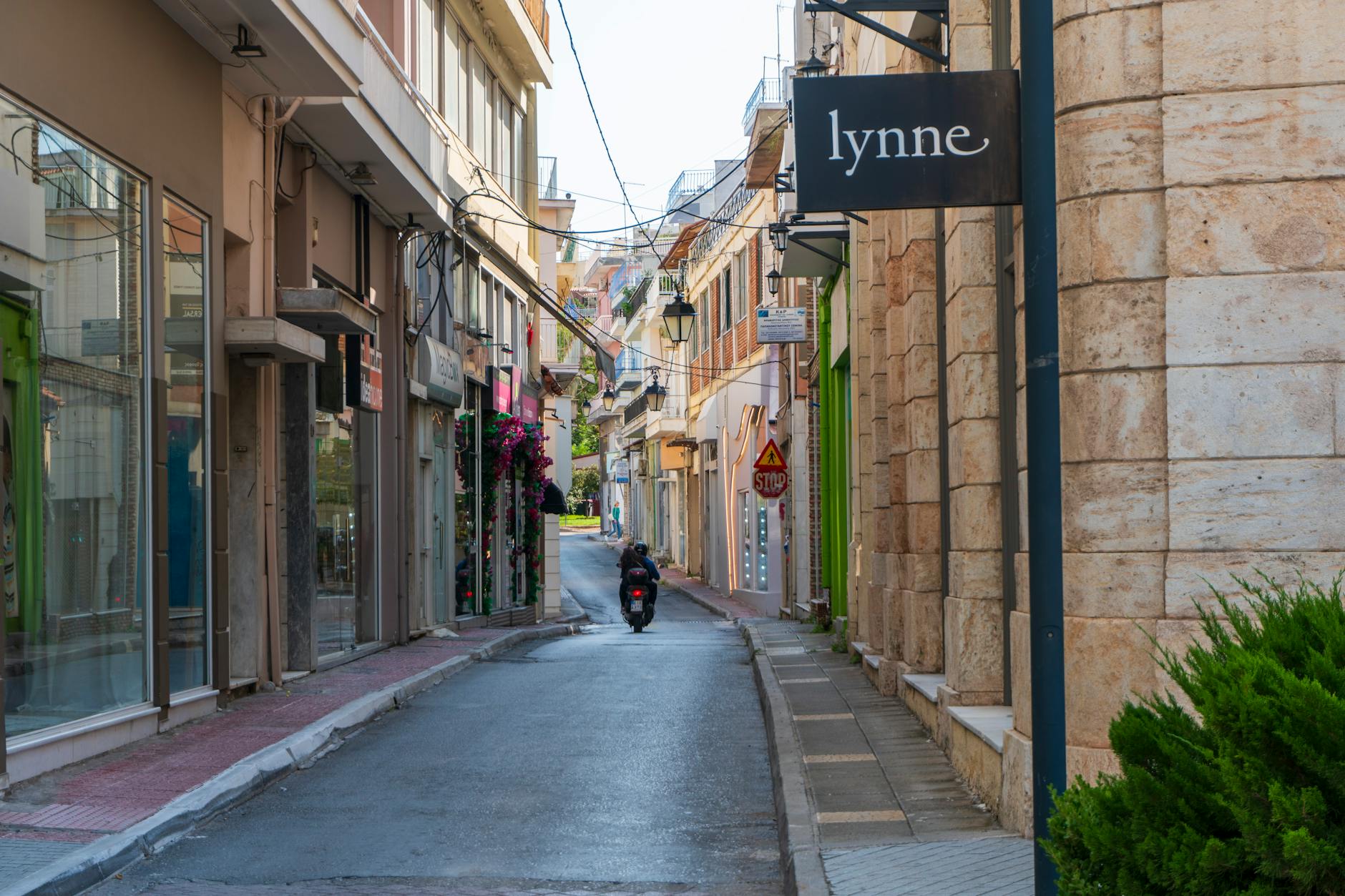A picturesque narrow street lined with shops and a motorcyclist in an urban setting.