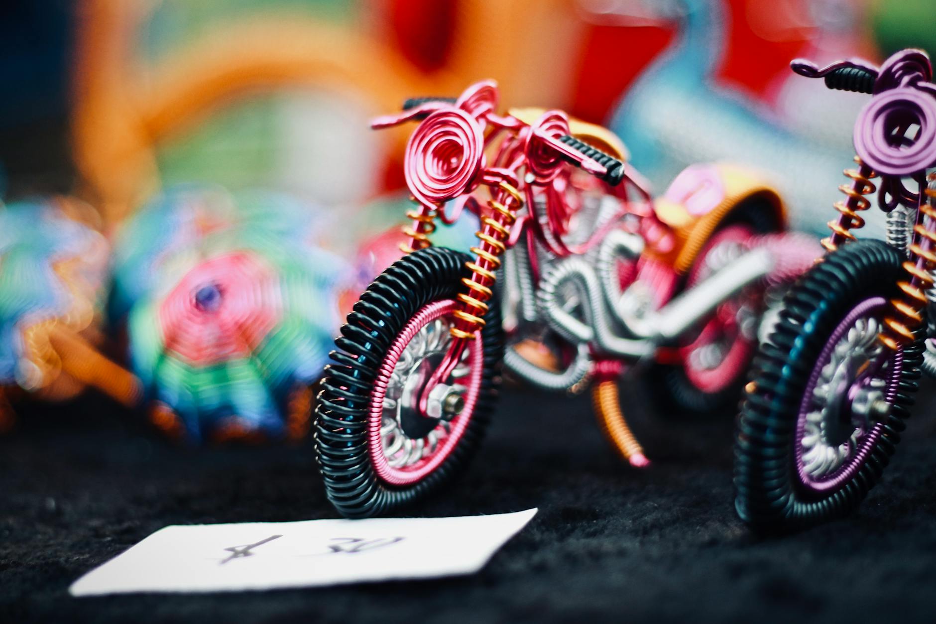 Artistic shot of wire-crafted motorbike models with vibrant colors and intricate details.