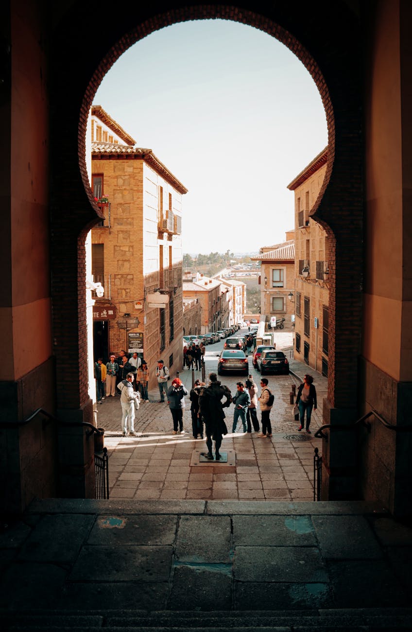View through a medieval archway onto a bustling Spanish street in Toledo, Spain.