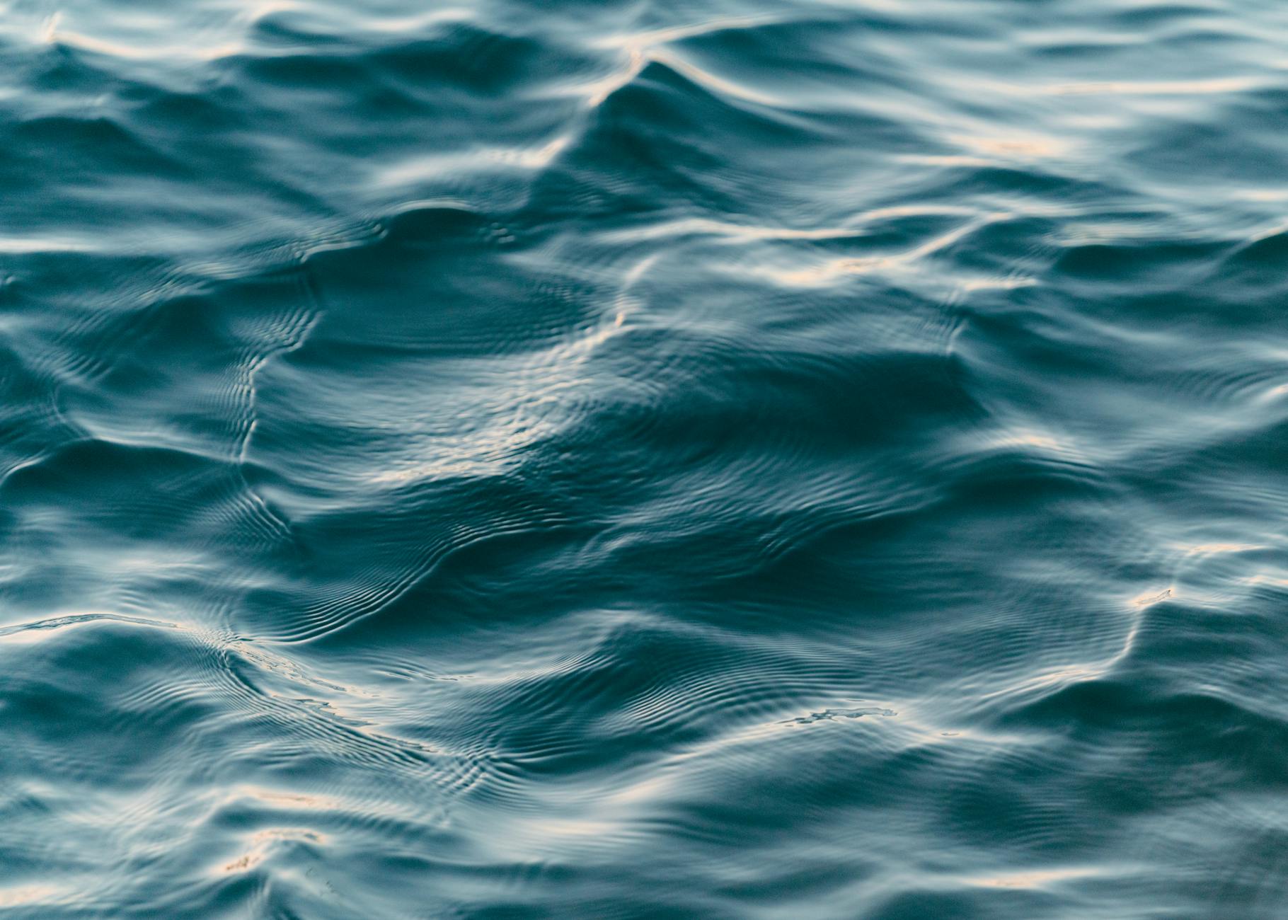 Calm blue ocean waves creating a soothing ripple texture, ideal for backgrounds.