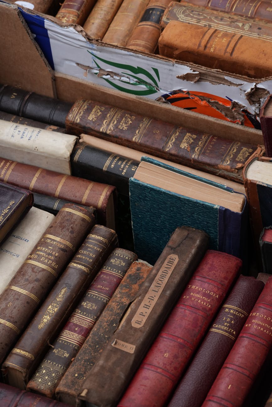 Vintage hardcover books in a worn cardboard box. Perfect for antique or literature enthusiasts.