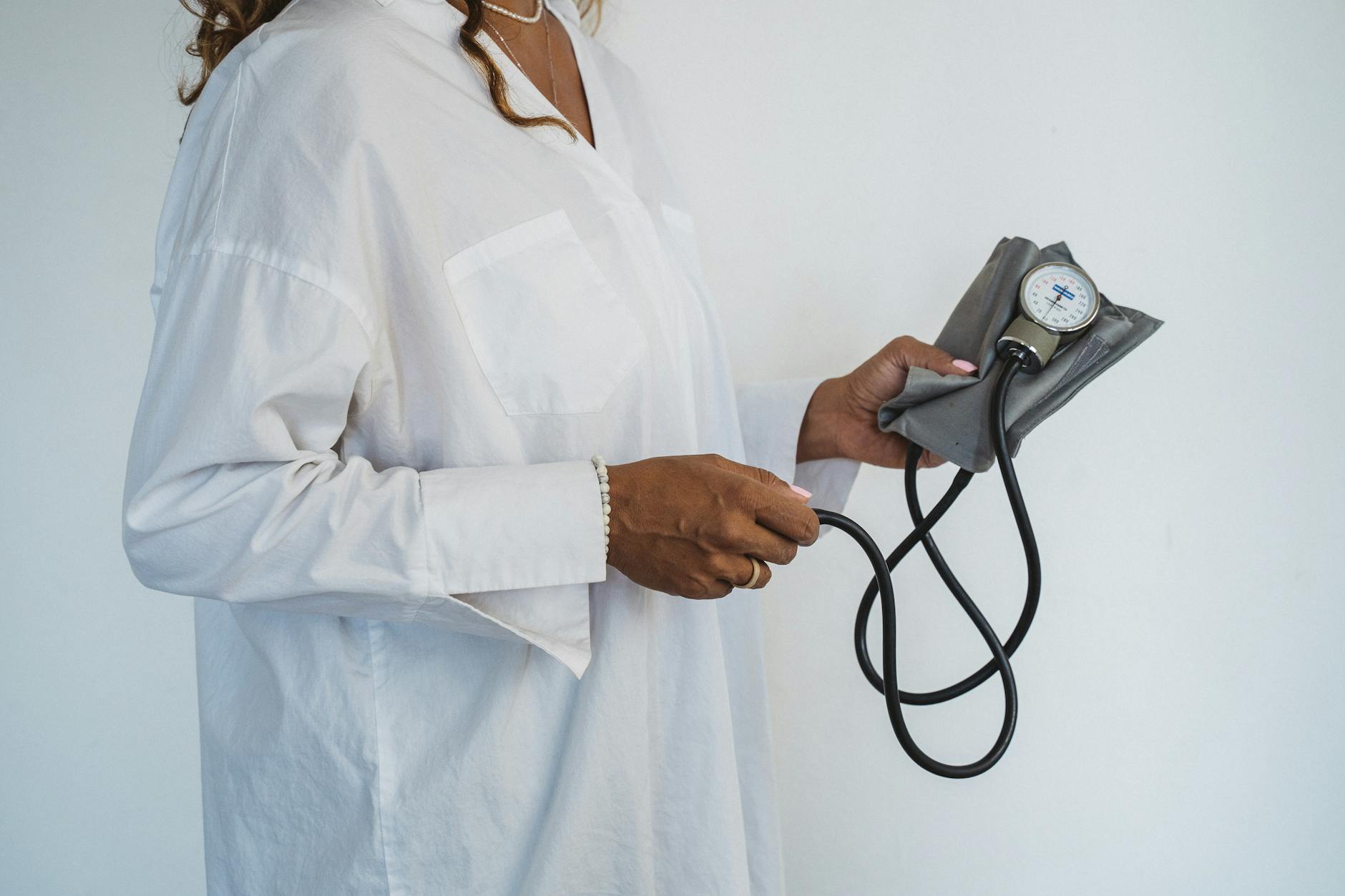 A healthcare professional in white holding a sphygmomanometer, demonstrating medical care.