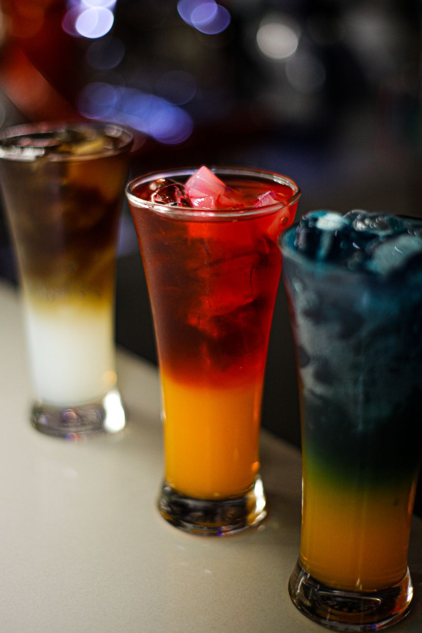 Colorful layered cocktails on display in a bar setting, showcasing vibrant beverages.