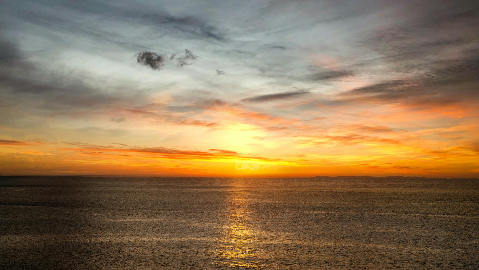 A serene ocean sunset with vivid colors reflecting on calm waters.