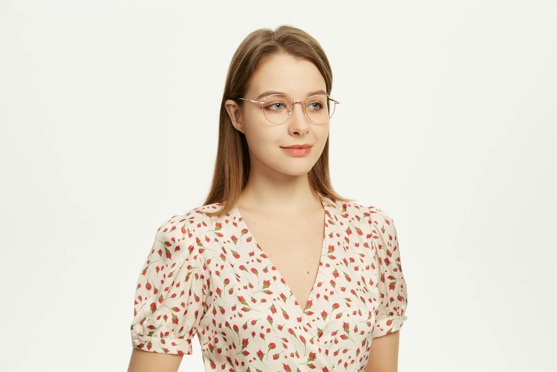 Portrait of a young woman in glasses and a floral blouse with soft lighting.