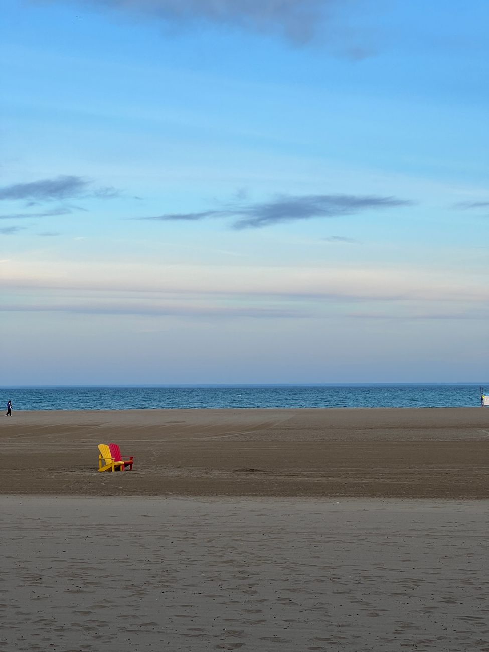 Peaceful beach scene with a colorful chair under a blue sky at Toronto's waterfront.