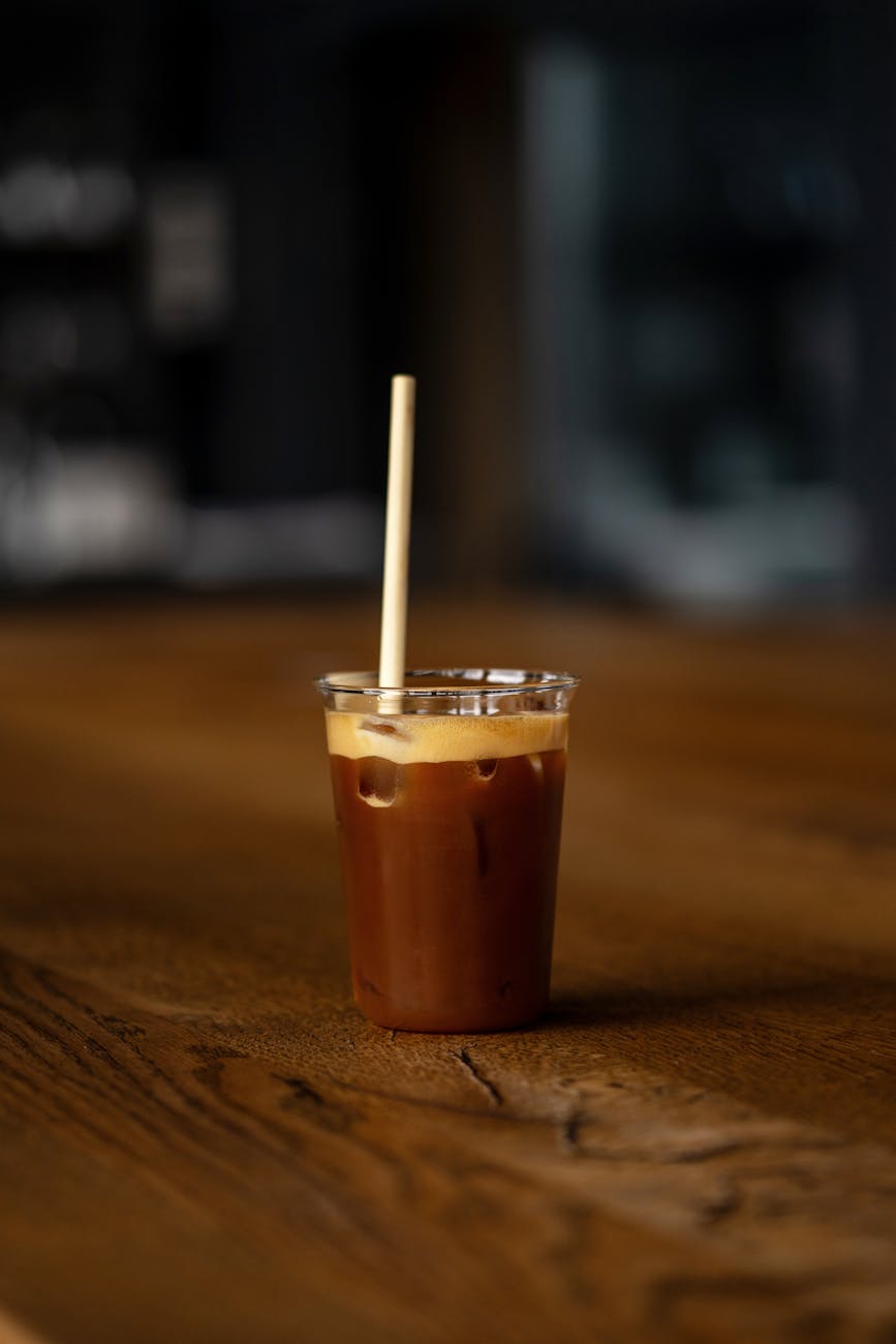 An inviting iced coffee in a clear cup on a wooden table, indoors.