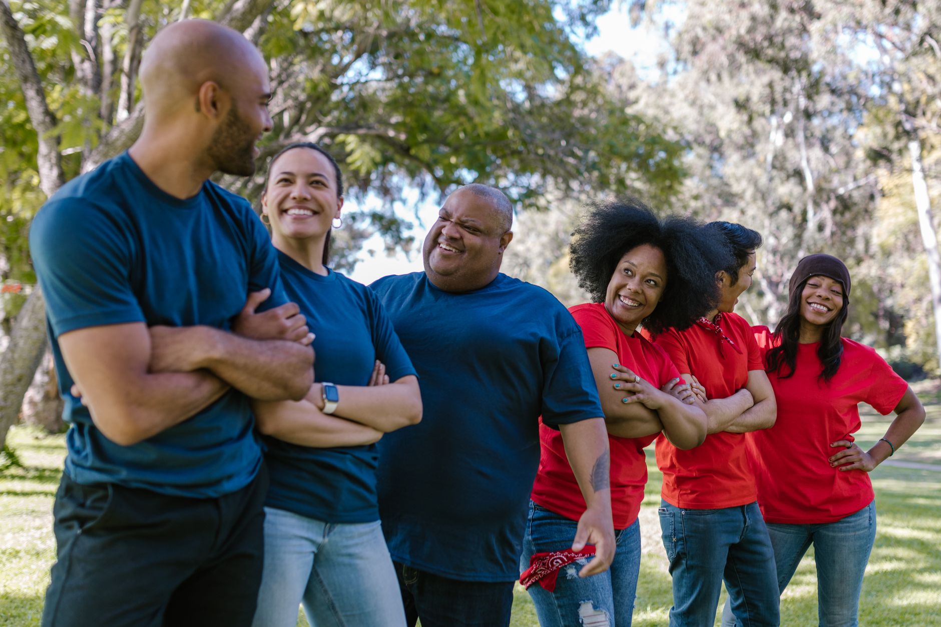 Diverse group of adults happily engage in outdoor team building activities on a sunny day.