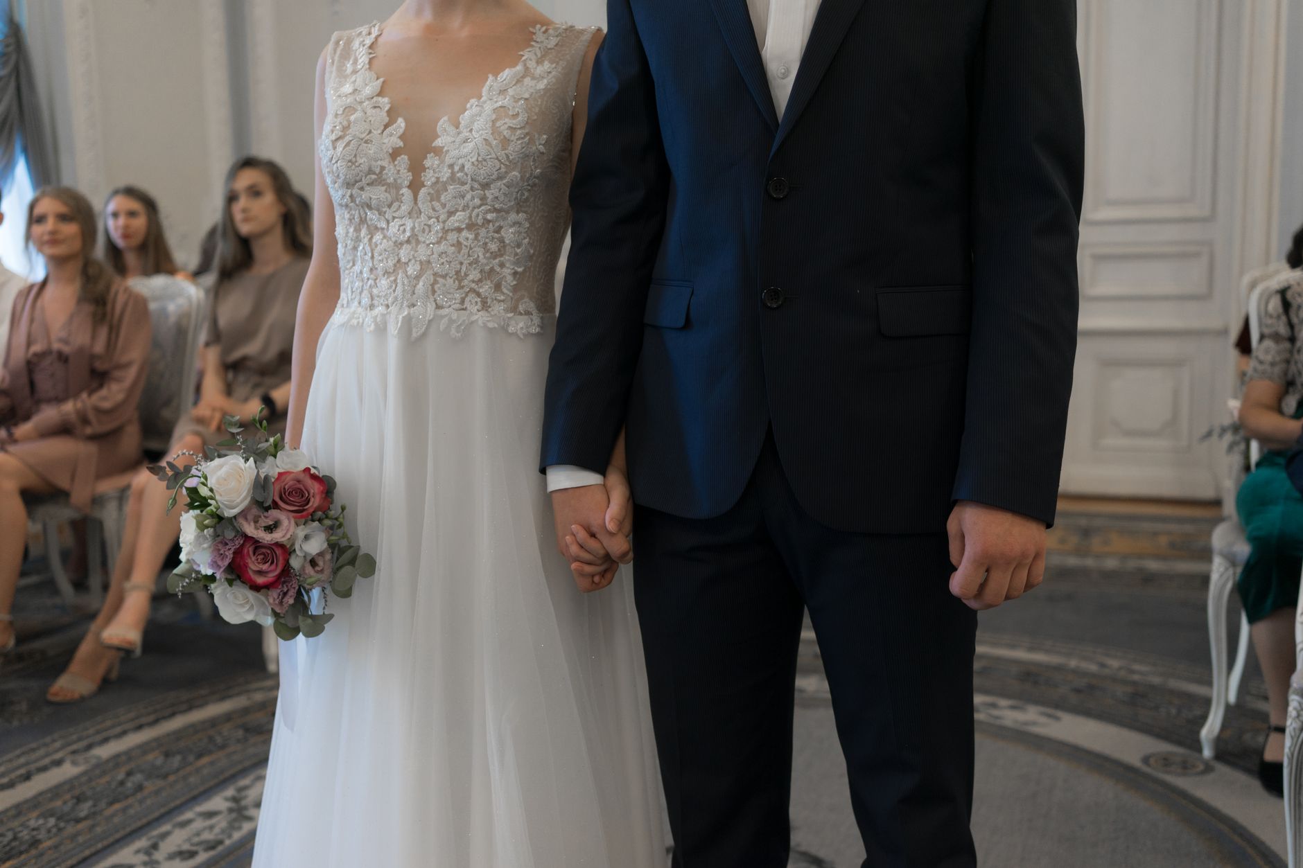 Bride and groom holding hands during an indoor wedding ceremony, capturing the essence of love and commitment.