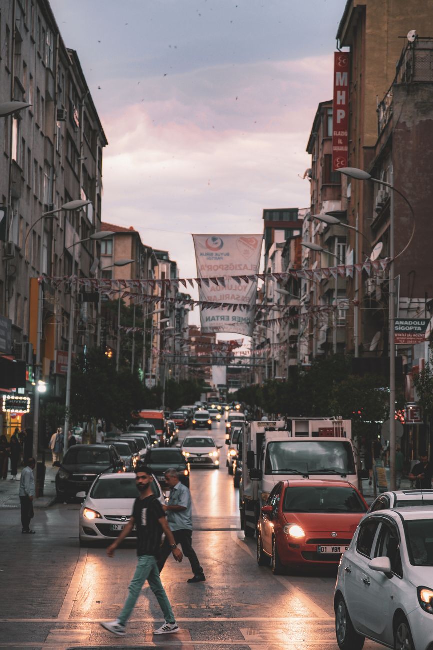City street bustling with traffic and pedestrians at dusk, capturing urban life.