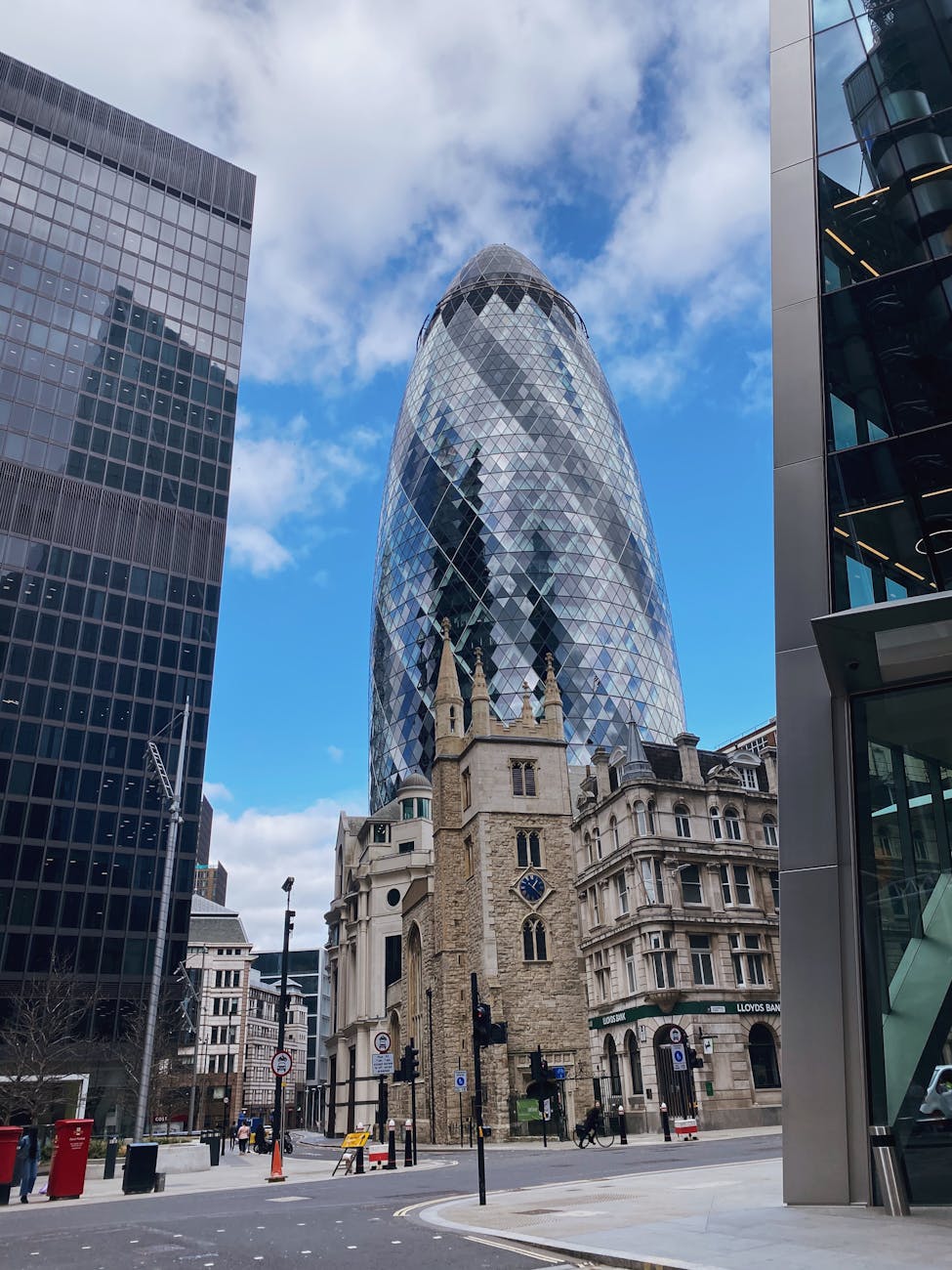 Low-angle view of the Gherkin and St. Andrew Undershaft church in London's financial district.