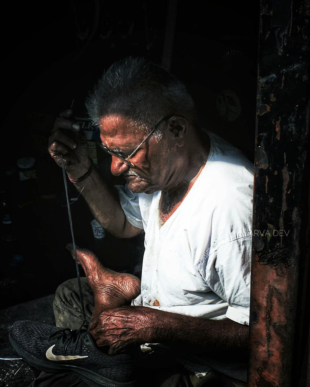 An elderly cobbler meticulously repairing a shoe in Pune, India.