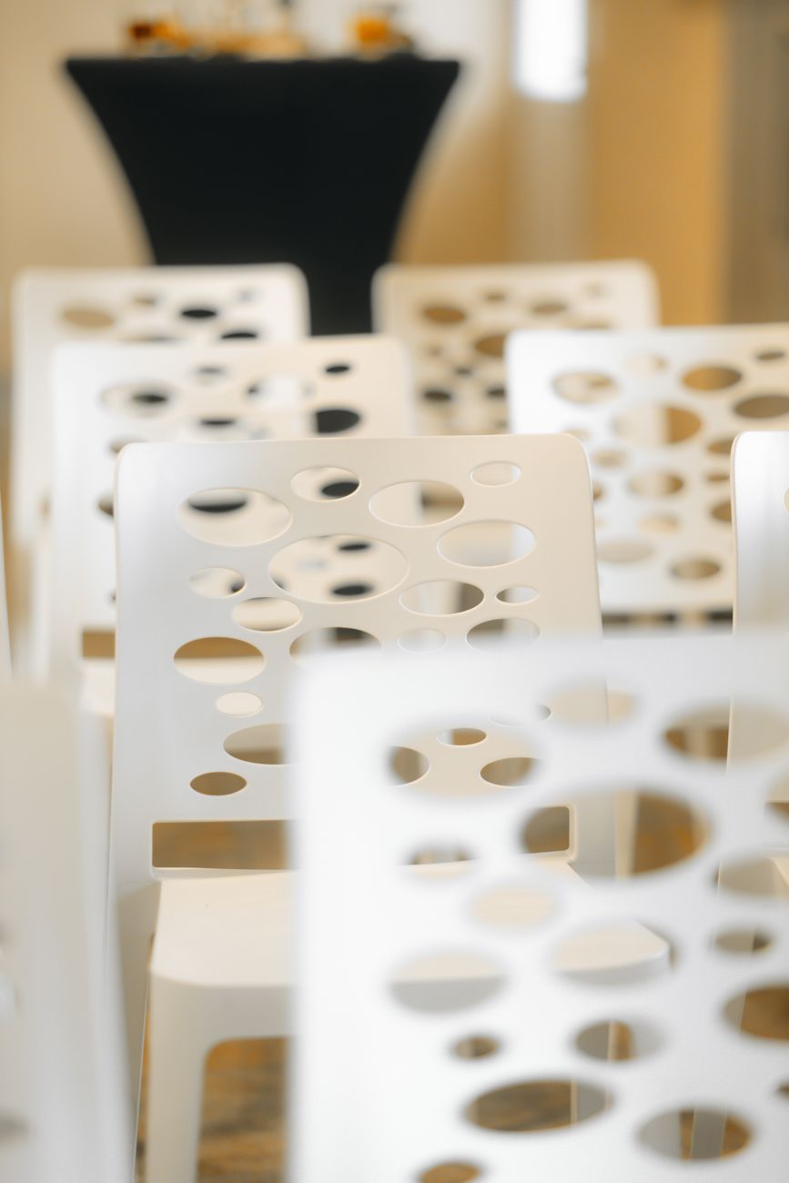 Modern white chairs with artistic design in an indoor conference venue.