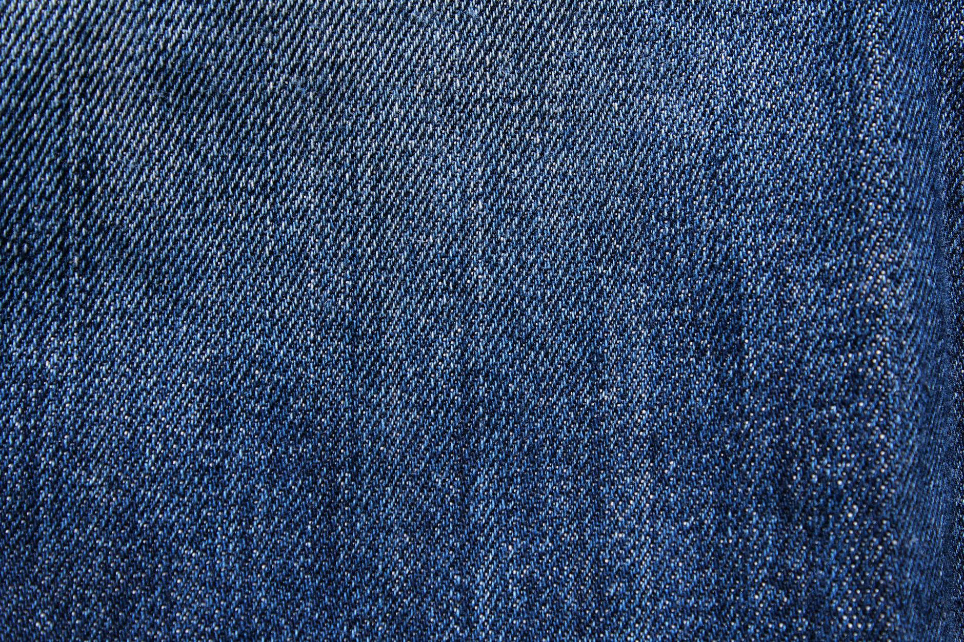 Textured blue denim fabric with detailed weaving visible in close-up macro view.