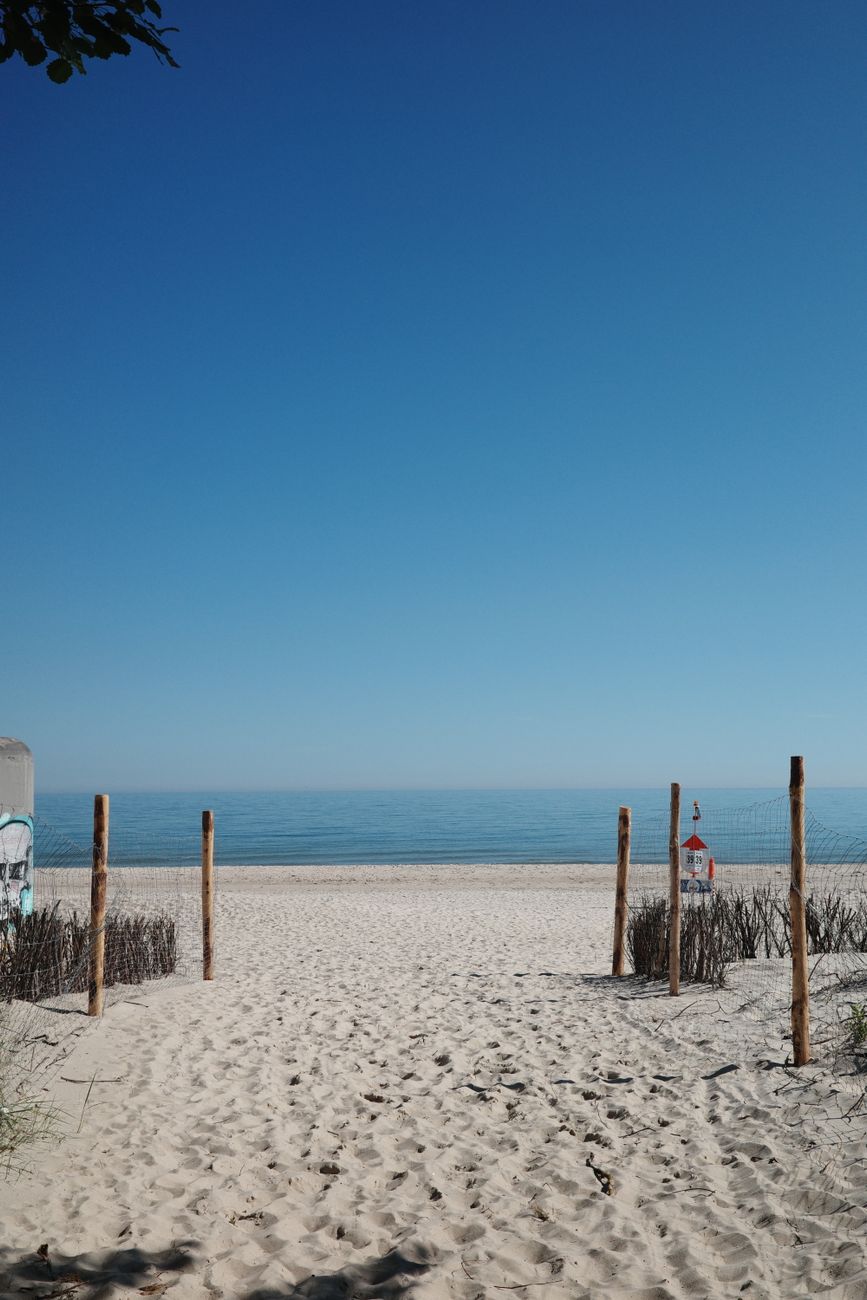 Peaceful beach access leading to a serene view of the sea and clear sky in Hel, Poland.