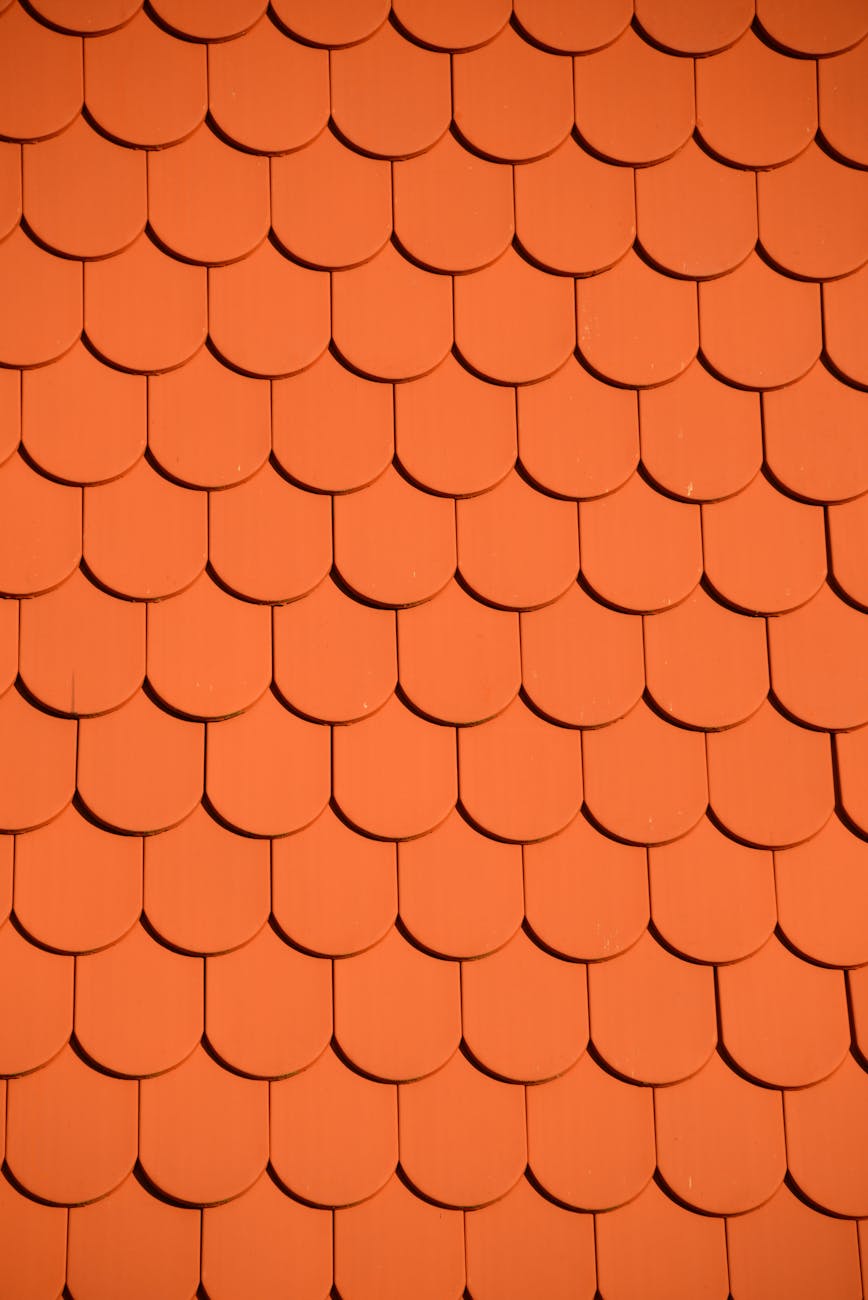 Bright orange roof tiles arranged in a seamless repetitive pattern, perfect for backgrounds and designs.