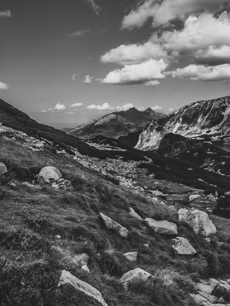 Black and white photo of Zakopane's rugged mountains, showcasing clouds and rocky terrain.