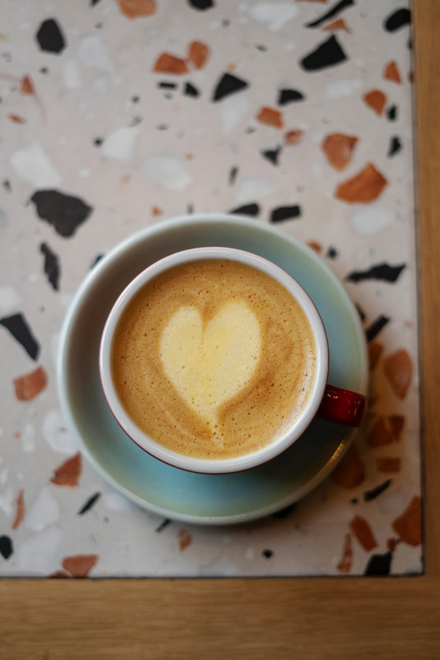 Top view of a cappuccino with heart-shaped foam in a blue cup, perfect for coffee lovers.