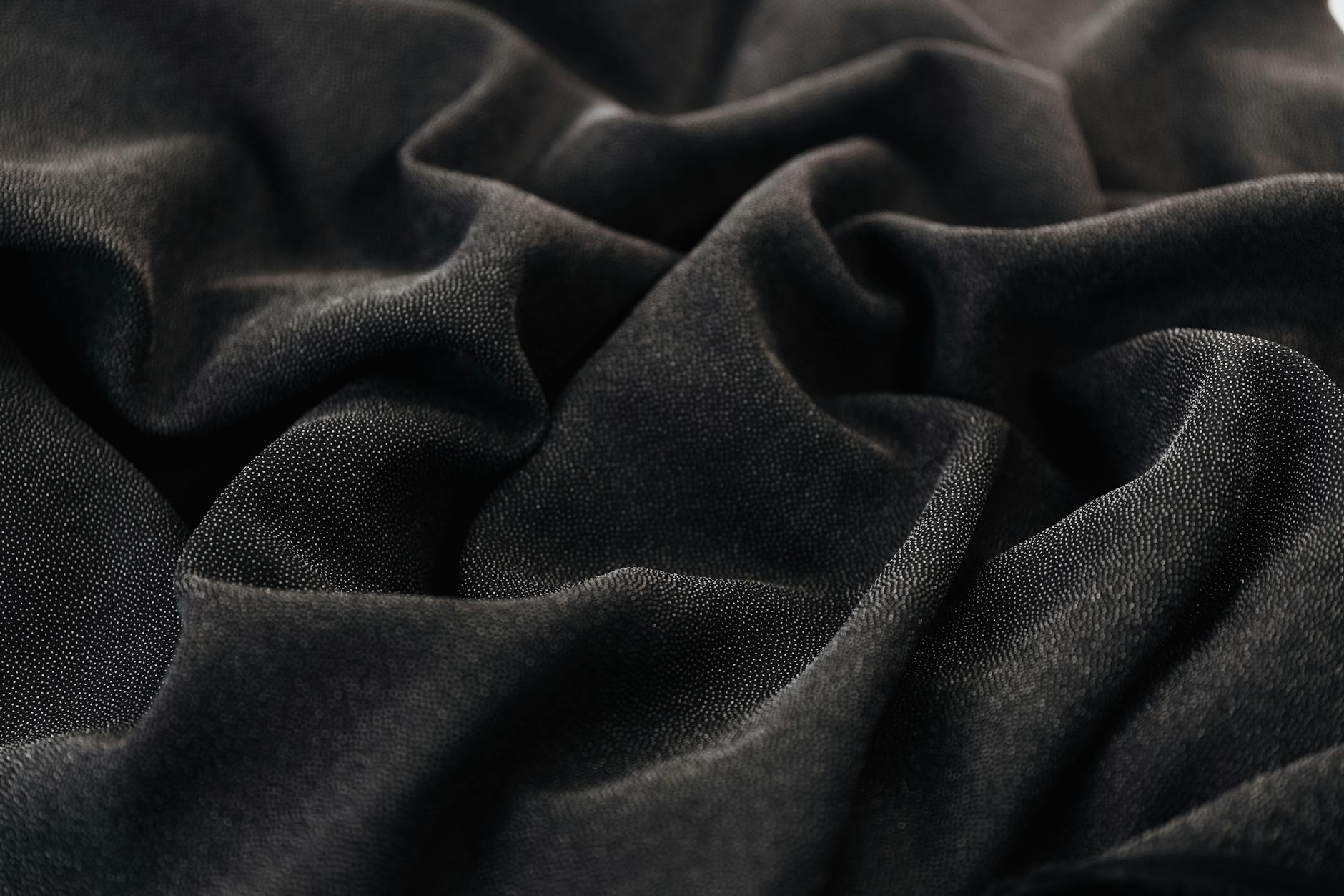 High-quality black fabric with intricate folds and texture, ideal for backgrounds and design.