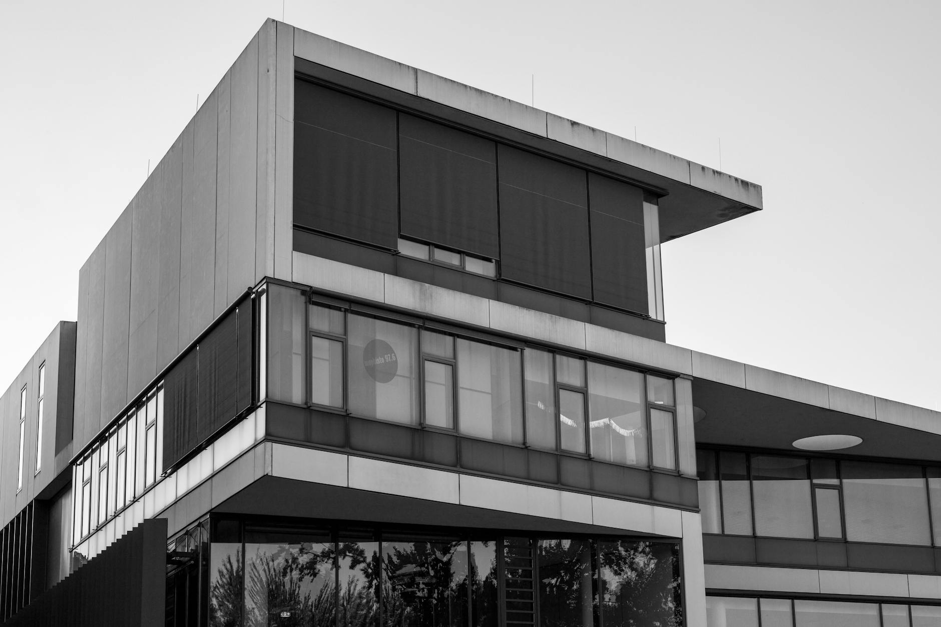 Sleek modern building showcasing geometric shapes and glass facade in black and white.