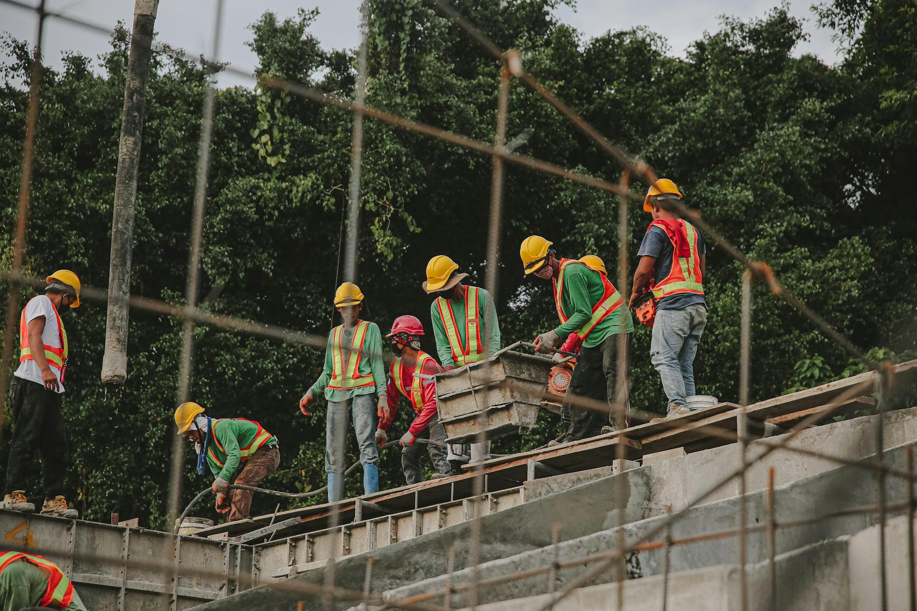 Construction workers in safety gear work on a structure outdoors, emphasizing teamwork and safety.