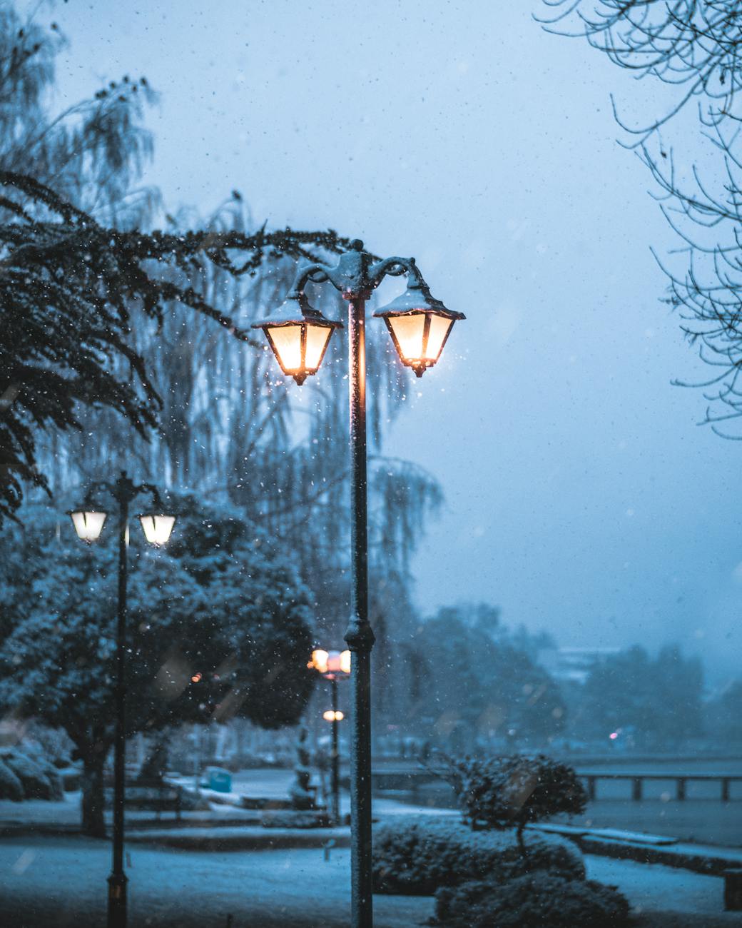 A tranquil winter scene in Ohrid, North Macedonia, featuring street lamps glowing amidst gentle snowfall.