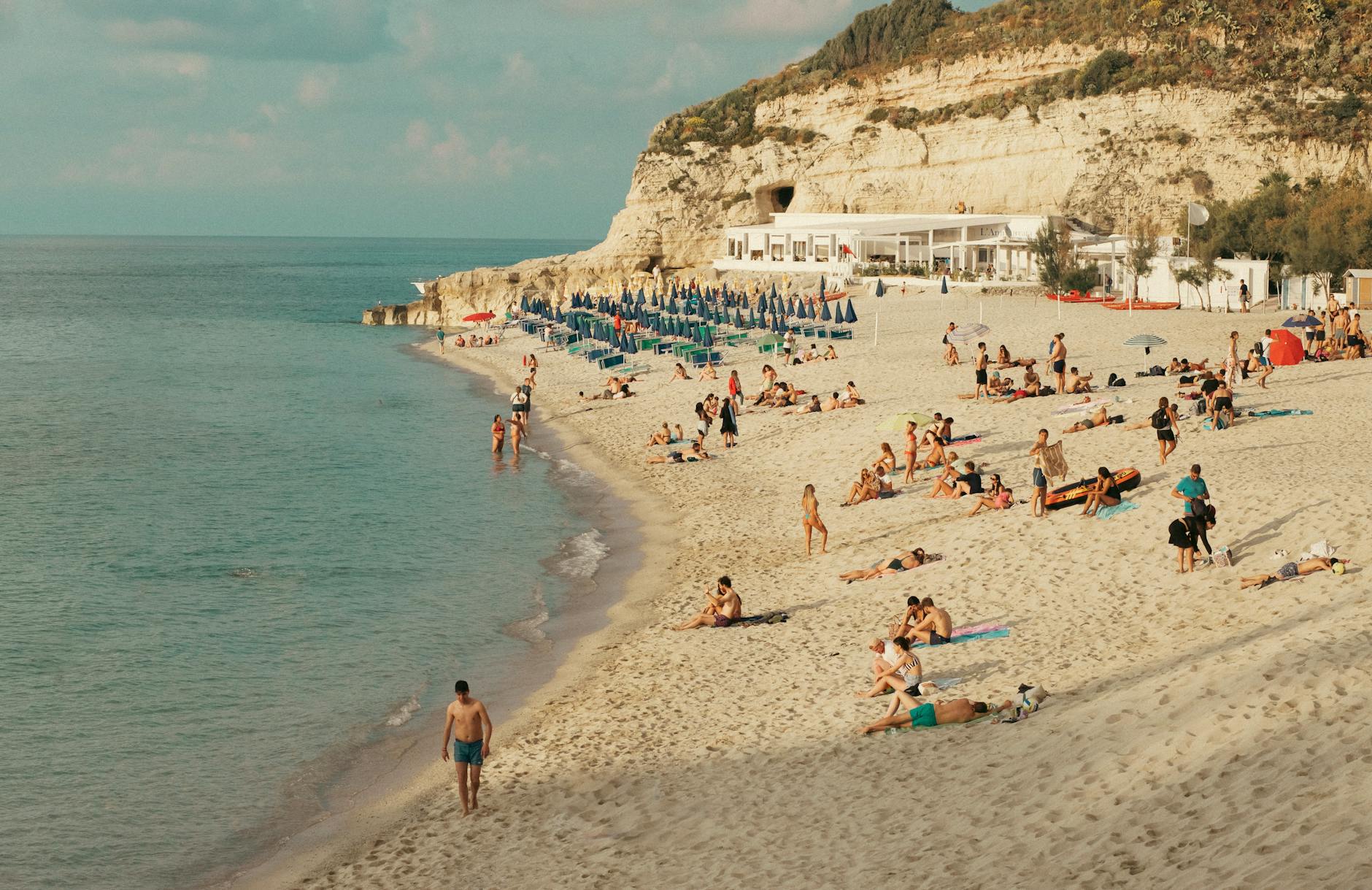 Sunny day at Tropea Beach, Calabria, featuring people enjoying sand and sea.