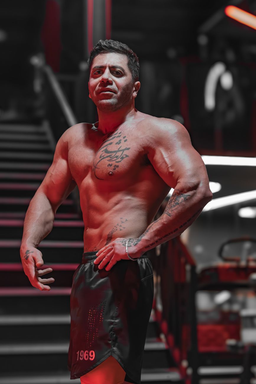 Tattooed bodybuilder posing confidently in a stylish gym environment.