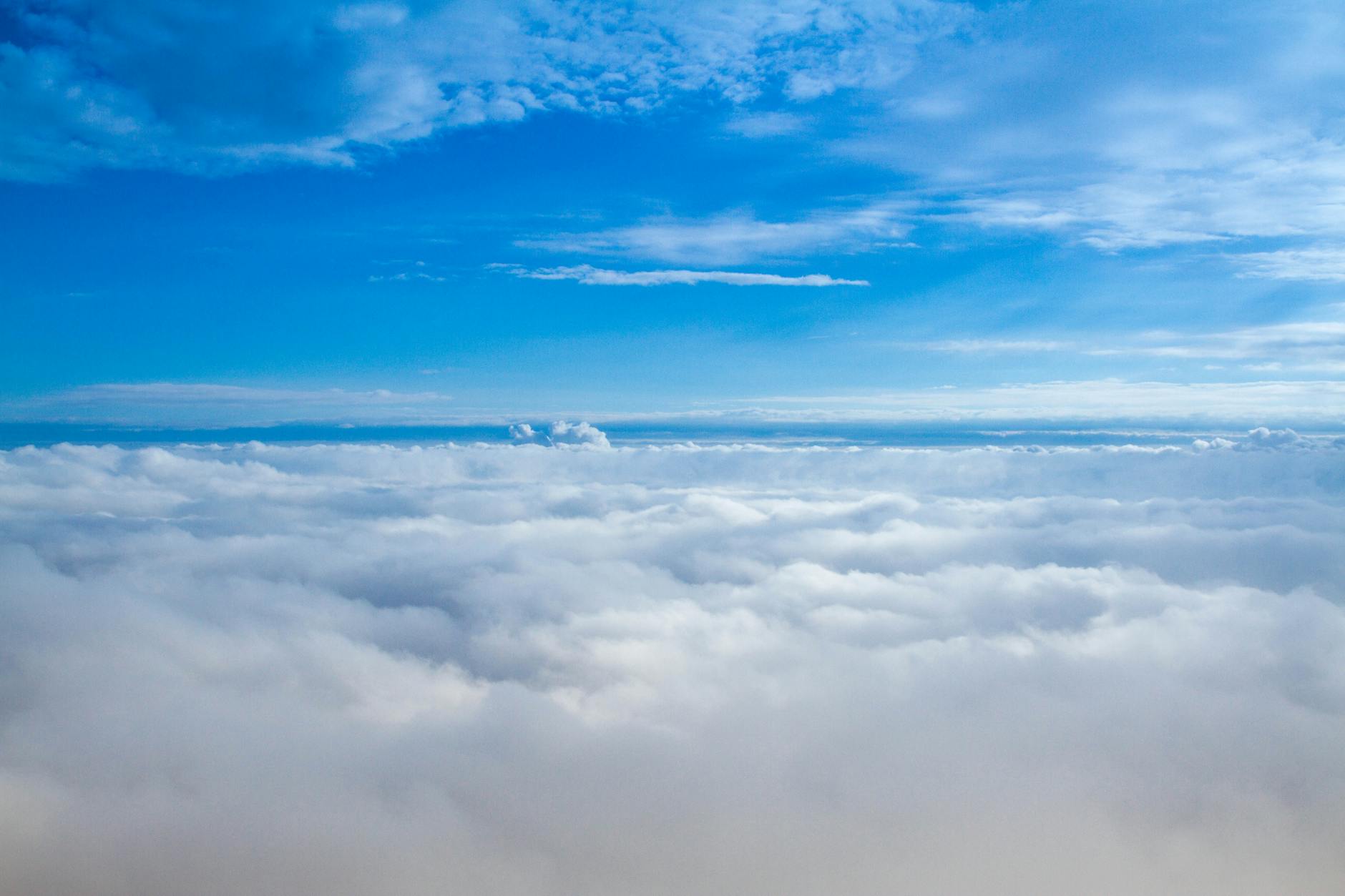 A stunning aerial view of fluffy clouds under a bright blue sky, captured in daylight.