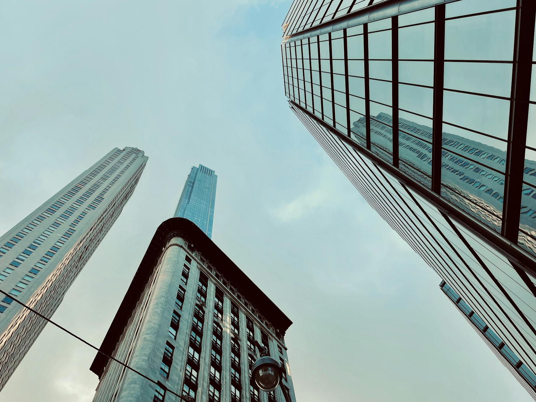 Low-angle shot of New York City skyscrapers reflecting the clear sky, showcasing urban architecture.