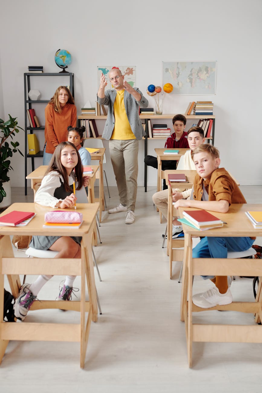 Teacher interacting with diverse group of students in modern classroom setting.